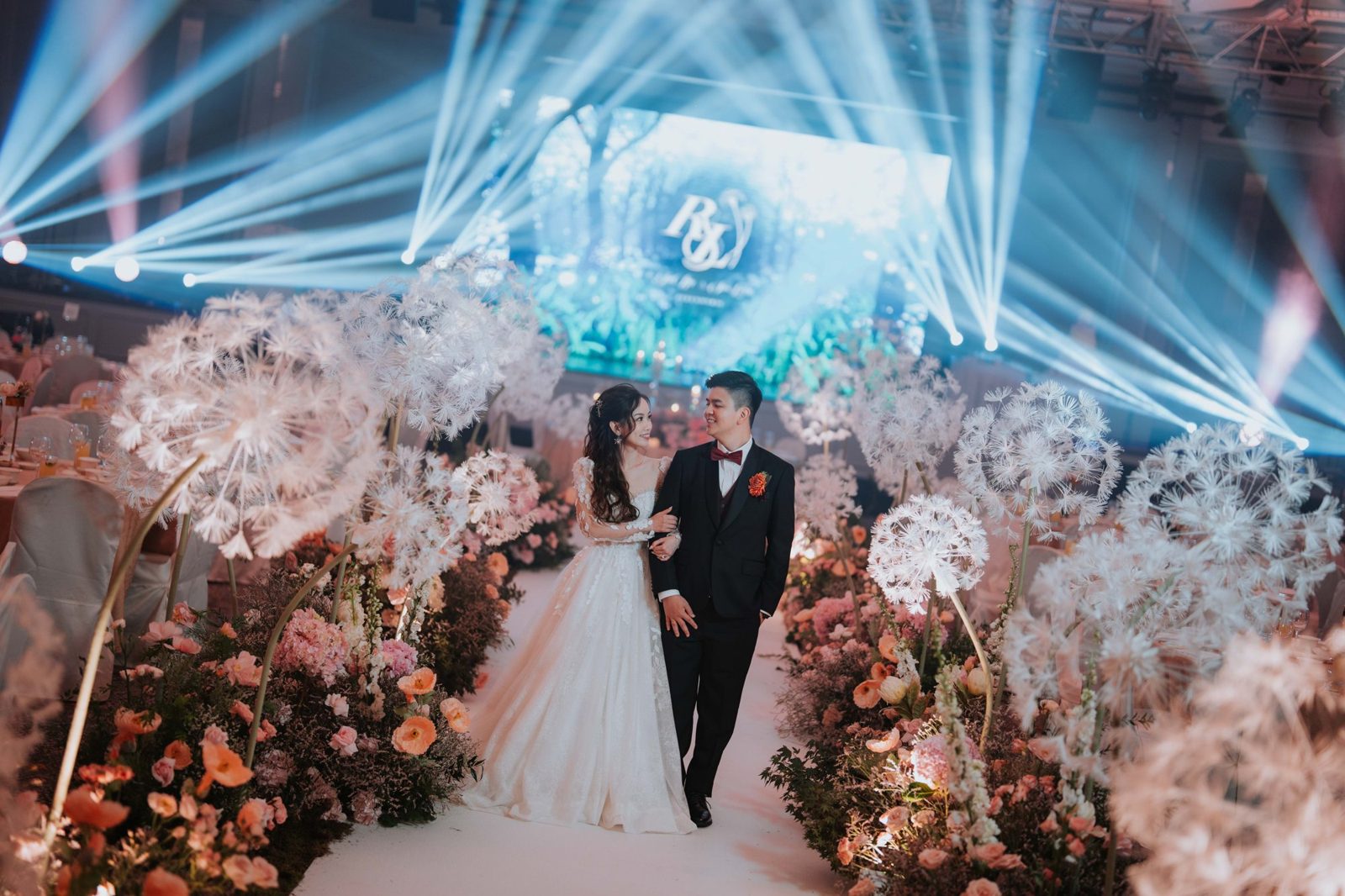 Couple walking through a dandelion floral aisle